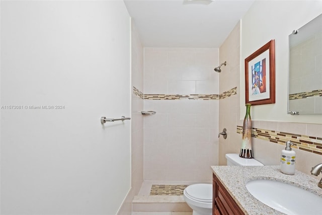 bathroom featuring a tile shower, vanity, tile walls, and toilet