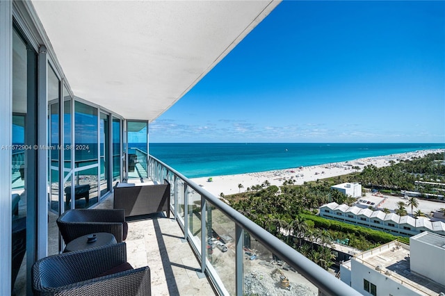 balcony with a water view and a view of the beach