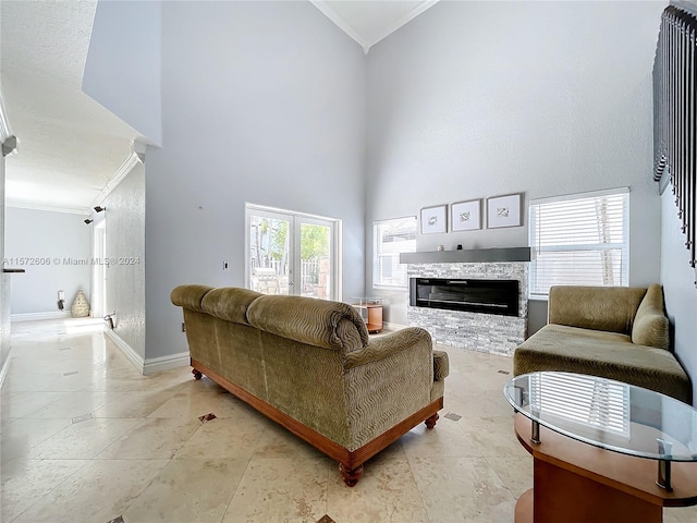 living room featuring a high ceiling, a stone fireplace, ornamental molding, and light tile patterned flooring