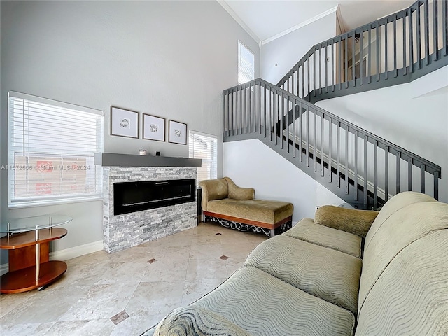 living room with plenty of natural light, a stone fireplace, ornamental molding, and a towering ceiling