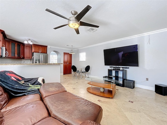 living room with ceiling fan, ornamental molding, and a textured ceiling