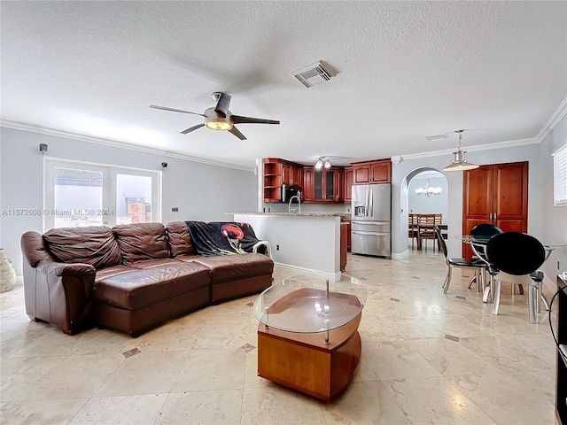 living room with ceiling fan, ornamental molding, and a textured ceiling