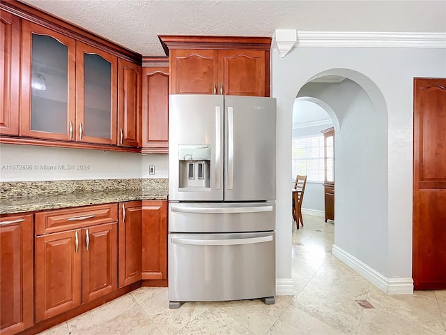 kitchen with stone counters, stainless steel fridge with ice dispenser, a textured ceiling, light tile patterned floors, and ornamental molding