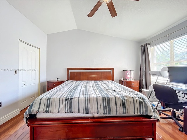 bedroom with vaulted ceiling, a closet, light hardwood / wood-style flooring, and ceiling fan