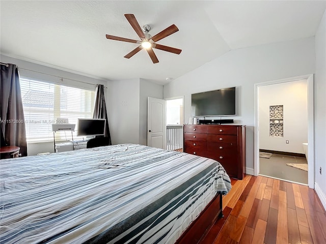 bedroom with hardwood / wood-style floors, connected bathroom, vaulted ceiling, and ceiling fan