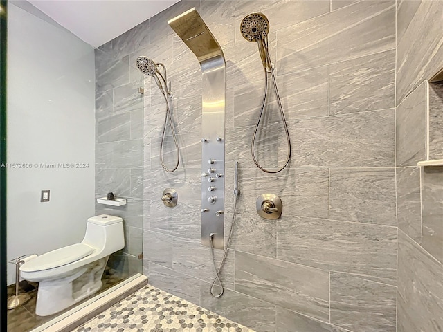 bathroom with a tile shower and toilet