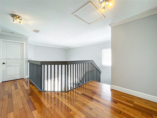 hall with hardwood / wood-style floors, crown molding, and a textured ceiling