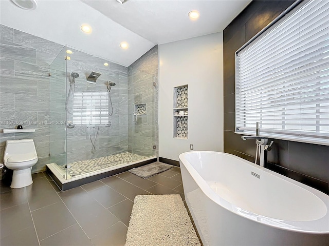 bathroom with vaulted ceiling, tile patterned flooring, separate shower and tub, toilet, and tile walls