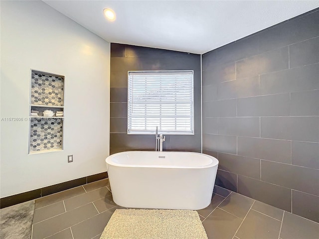 bathroom with tile patterned flooring, a bath, vaulted ceiling, and tile walls