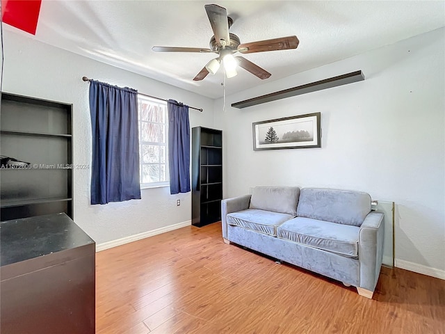 living room with hardwood / wood-style flooring, ceiling fan, and a textured ceiling