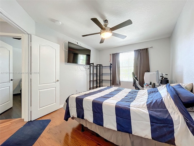 bedroom featuring hardwood / wood-style flooring, ceiling fan, and a textured ceiling