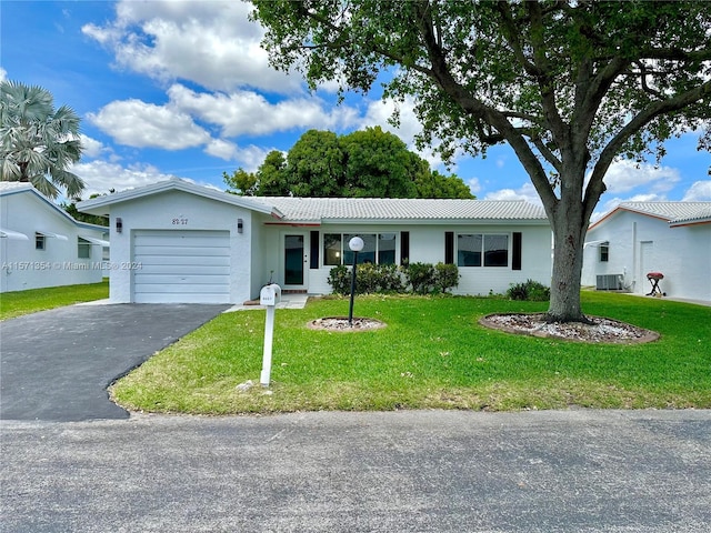 ranch-style home featuring central AC unit, a garage, and a front lawn