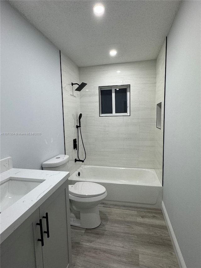 full bath with bathing tub / shower combination, toilet, vanity, wood finished floors, and baseboards