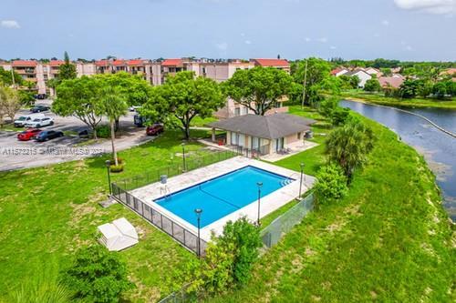 view of swimming pool with a water view, a patio area, and a lawn