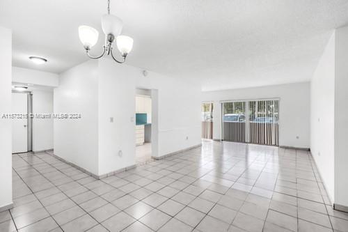 tiled empty room featuring a notable chandelier