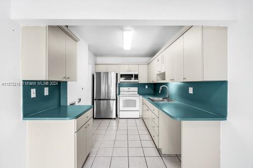 kitchen with stainless steel appliances, light tile patterned flooring, sink, and decorative backsplash