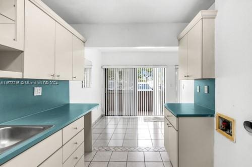 kitchen featuring white cabinetry, light tile patterned floors, and sink