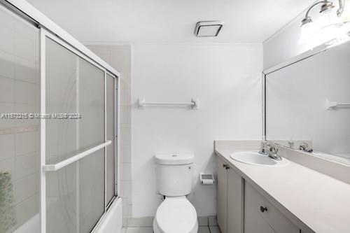 full bathroom featuring vanity, tile patterned flooring, shower / bath combination with glass door, and toilet