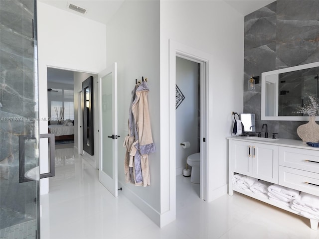 bathroom featuring tile flooring, a shower with door, vanity, and toilet