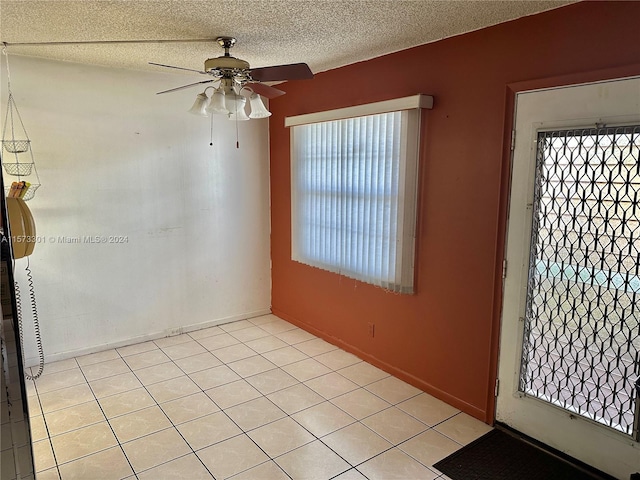 tiled empty room featuring a textured ceiling and ceiling fan