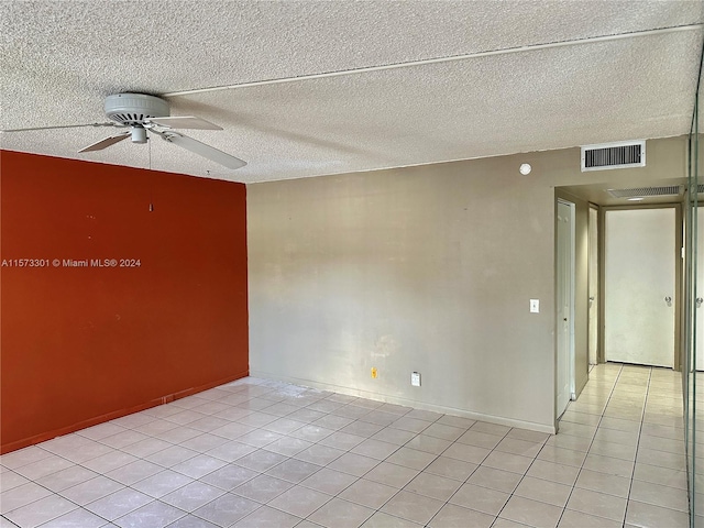 empty room with ceiling fan, tile floors, and a textured ceiling