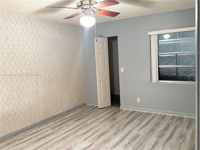 empty room featuring light hardwood / wood-style floors, ceiling fan, and a textured ceiling