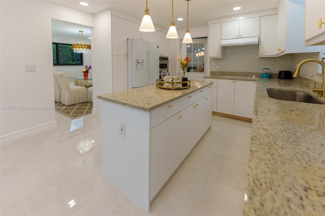 kitchen with sink, a center island, white cabinets, and white fridge with ice dispenser