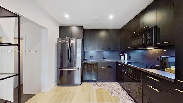 kitchen featuring light hardwood / wood-style flooring, black appliances, backsplash, dark brown cabinets, and sink