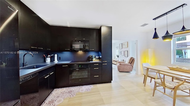 kitchen with stainless steel counters, hanging light fixtures, black appliances, sink, and tasteful backsplash