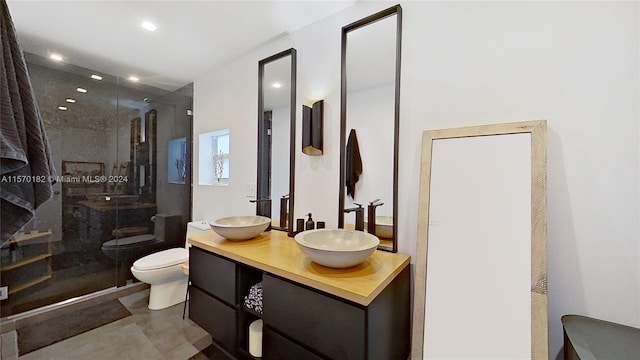 bathroom featuring tile flooring, a shower with door, vanity, and toilet