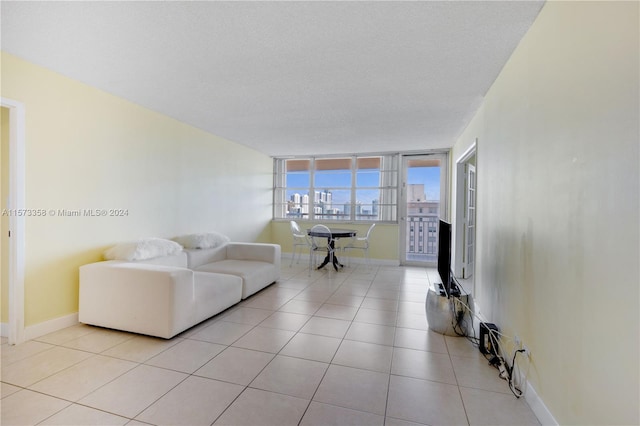 tiled living room featuring a textured ceiling and a wall of windows