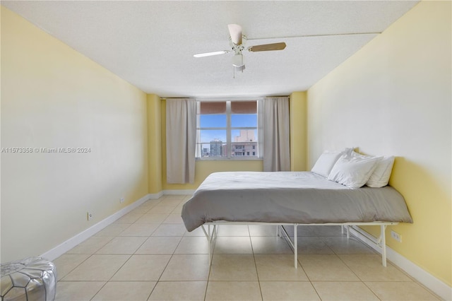 bedroom featuring ceiling fan, a textured ceiling, and light tile patterned flooring