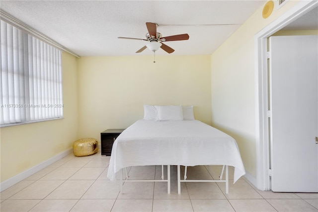 tiled bedroom with ceiling fan and a textured ceiling