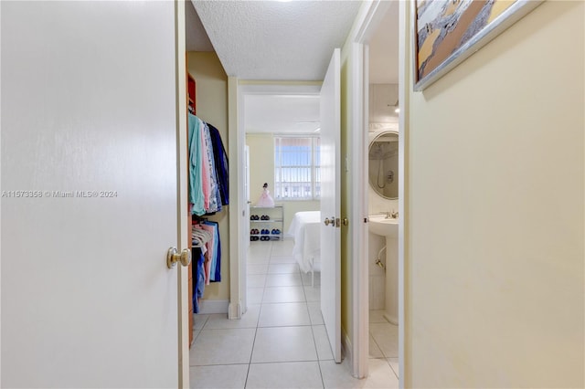 corridor featuring a textured ceiling and light tile patterned floors