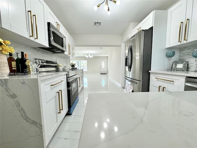 kitchen with decorative backsplash, light stone countertops, white cabinetry, and appliances with stainless steel finishes