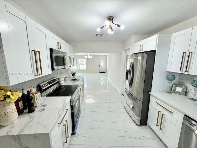 kitchen featuring white cabinets, tasteful backsplash, an inviting chandelier, and stainless steel appliances