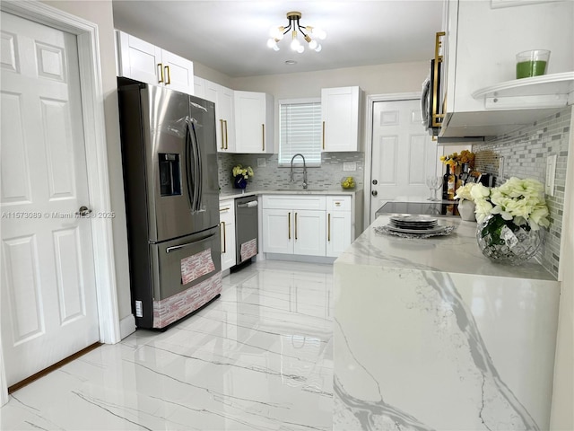 kitchen with sink, tasteful backsplash, white cabinetry, light stone counters, and stainless steel appliances