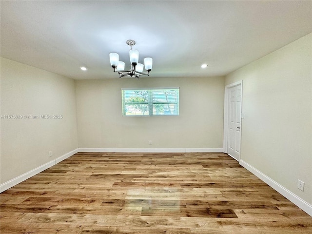 spare room featuring a notable chandelier and light hardwood / wood-style flooring