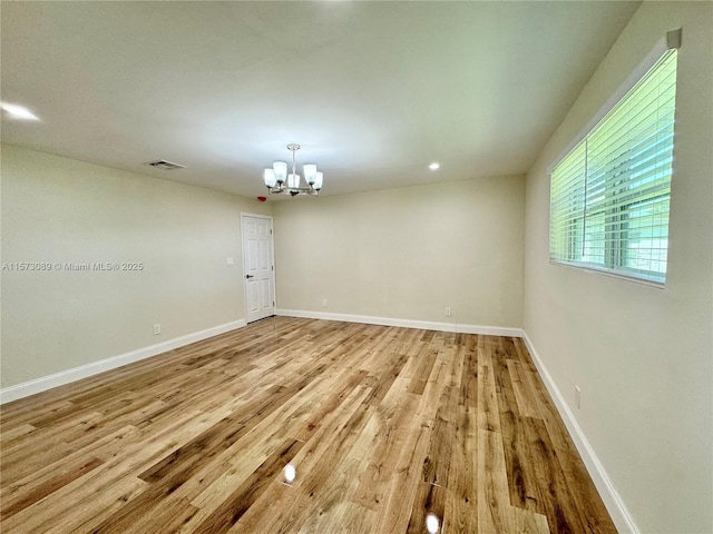 spare room with light hardwood / wood-style flooring and a notable chandelier