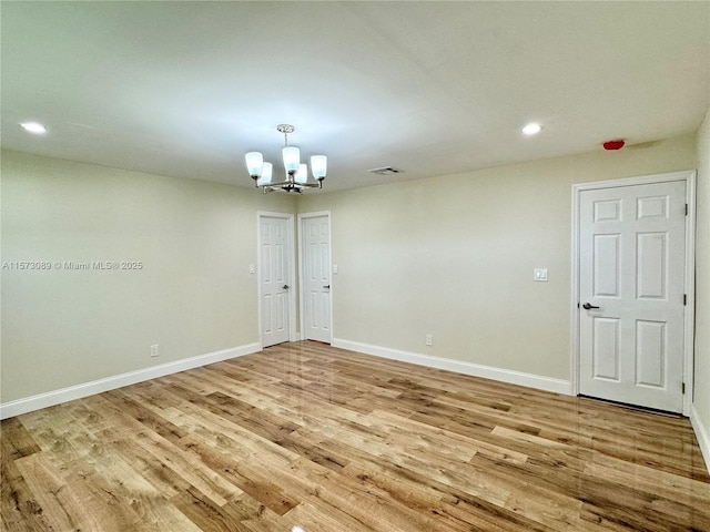 spare room featuring light hardwood / wood-style flooring and a notable chandelier