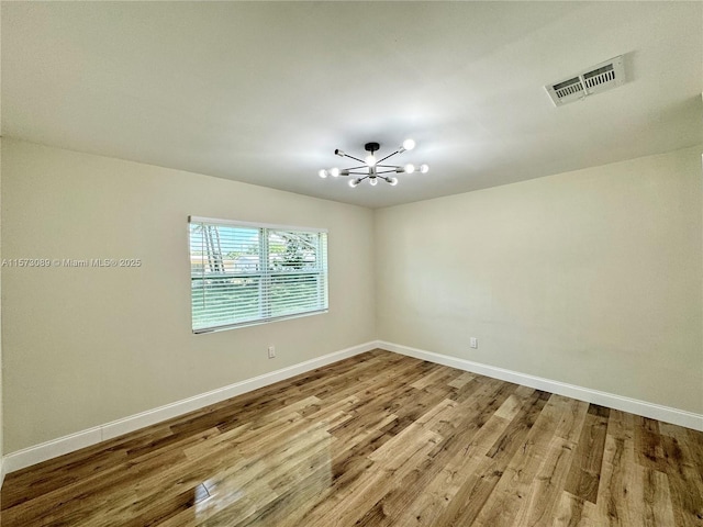 spare room with hardwood / wood-style flooring and a chandelier