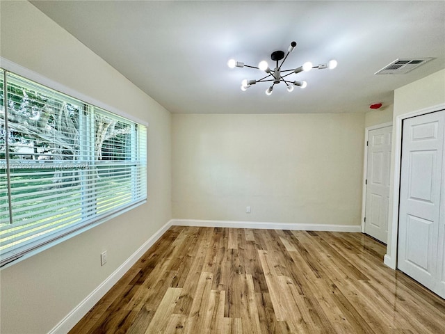 unfurnished bedroom featuring light hardwood / wood-style flooring and a chandelier