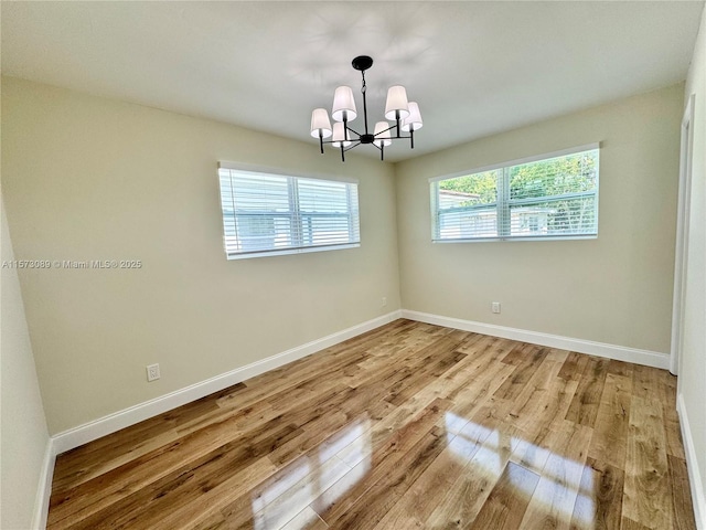 spare room with a chandelier and light hardwood / wood-style flooring