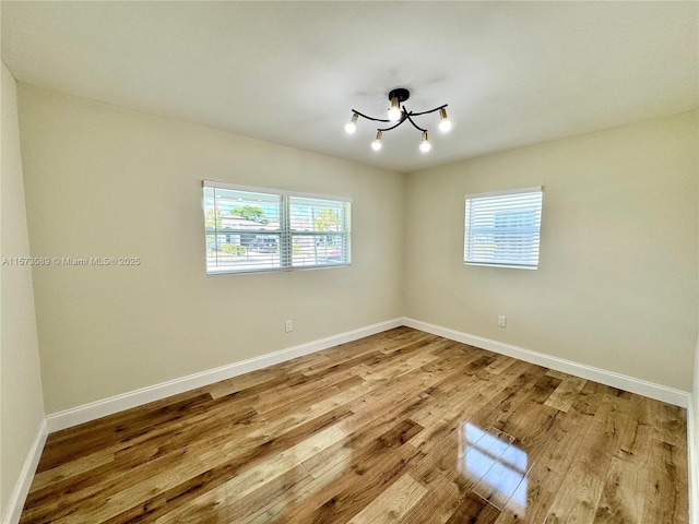 empty room with light hardwood / wood-style flooring and a chandelier