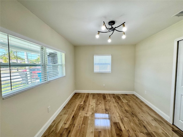 unfurnished dining area featuring a chandelier and light hardwood / wood-style floors