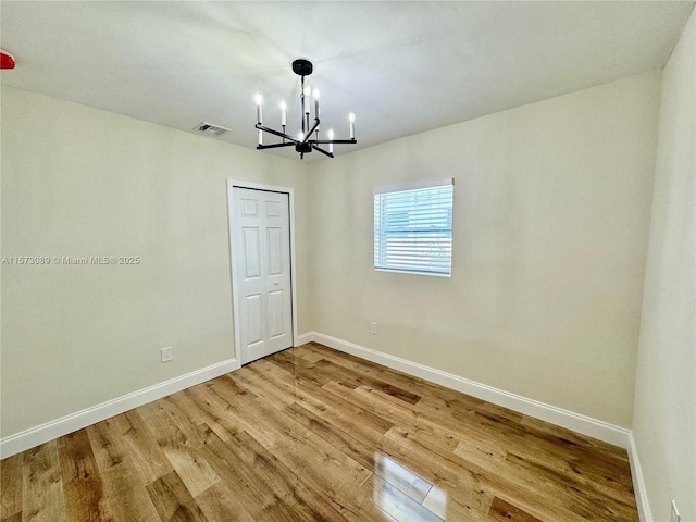 unfurnished room featuring wood-type flooring and a notable chandelier