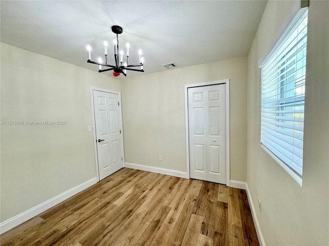 unfurnished bedroom with an inviting chandelier and light hardwood / wood-style flooring