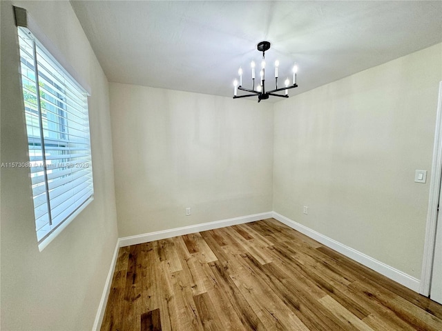 unfurnished dining area with hardwood / wood-style floors and an inviting chandelier