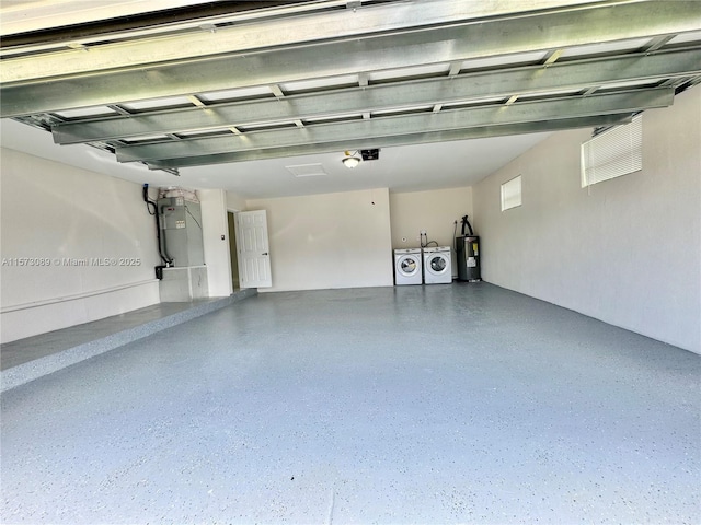 garage with heating unit, water heater, and washing machine and clothes dryer