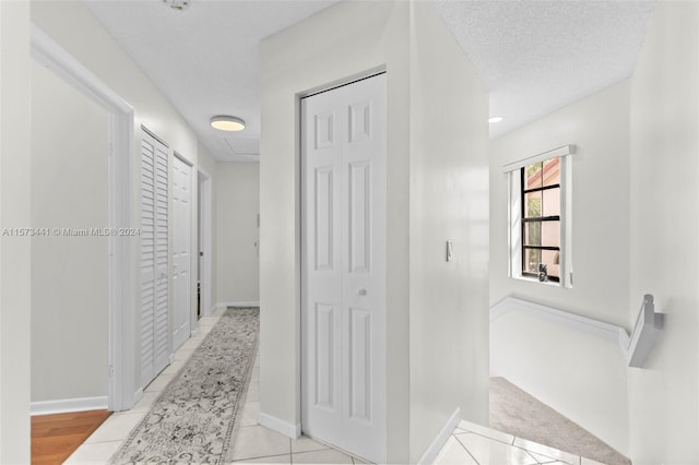 hall with light tile floors and a textured ceiling